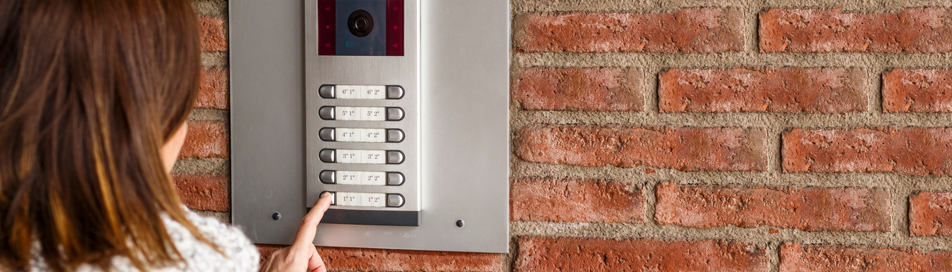 Woman Pushing Button of an Intercom